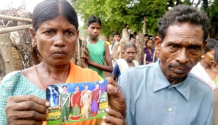 Parents of Madkam Hidme hold up a picture of their late daughter