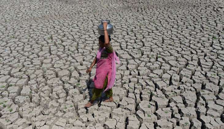 A woman walks on the parched bed of Chandola Lake with a metal pot on her head to fetch water in Ahmedabad on 20 May 2016. India is facing its worst water crisis in decades, with about 330 million people suffering from drought