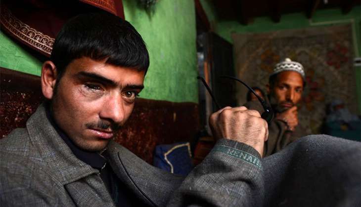 In this picturea taken on 22 March, 2013 eighteen year old Tariq Gojri (L) who lost his right eye to a pellet gun allegedly fired by Indian police officials poses with family members during an interview with AFP at his home in Khanpora.